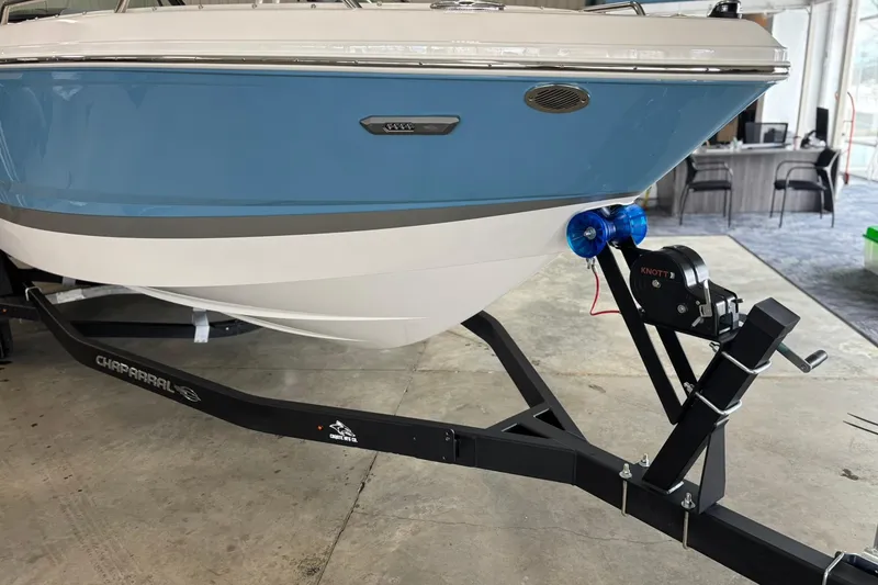 Slide: The Image of 2026 Chaparral SSX 4 boat on trailer in showroom, featuring sleek blue and white design. - 7
