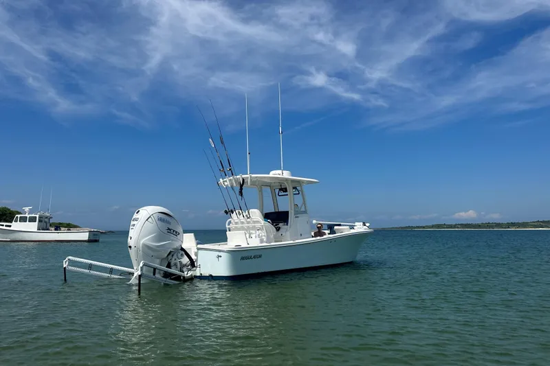 Slide: The Image of 2024 Regulator 26XO boat on calm water under a clear blue sky. - 2