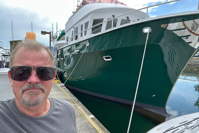 Slide: The Image of Man standing beside a 2004 Northern Marine 57 Raised Pilothouse yacht at a marina. - 44