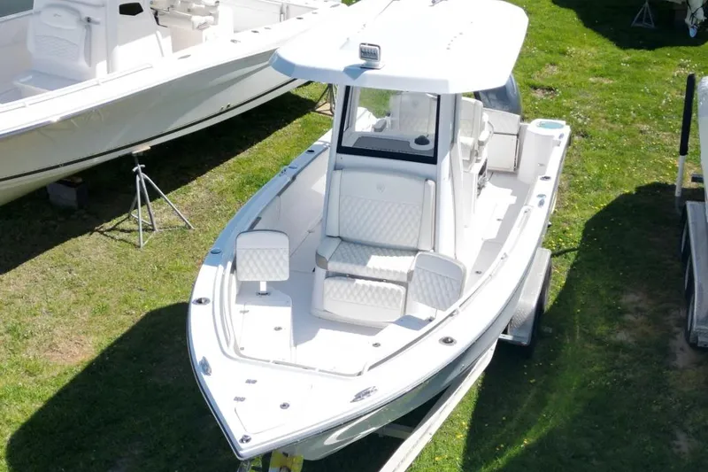 The Image of 2022 Century 2400 Center Console boat on trailer, parked on grass. - 1