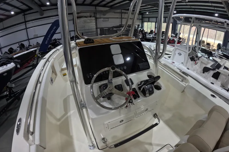Slide: The Image of 2026 Bulls Bay 255 Center Console boat interior with steering wheel and controls in showroom. - 10