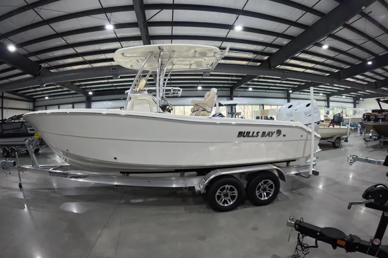 Slide: The Image of 2026 Bulls Bay 255 Center Console boat displayed in a spacious indoor showroom. - 2