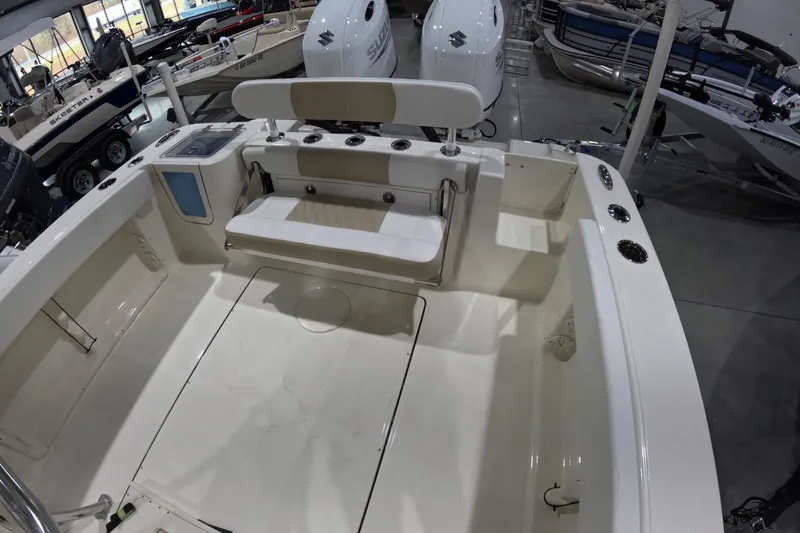 Slide: The Image of 2026 Bulls Bay 255 Center Console boat interior with seating and storage, displayed in showroom. - 8
