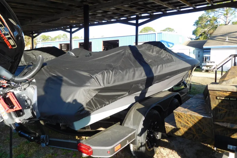 Slide: The Image of 2026 Skeeter ZXE21 boat covered, parked under shelter with Yamaha engine visible. - 2