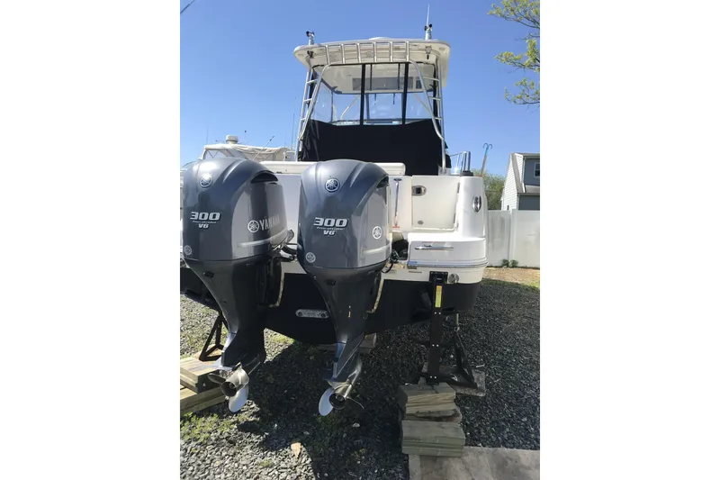 Slide: The Image of 2014 Robalo R305 Walkaround boat on stands, outdoors, surrounded by trees and buildings. - 5