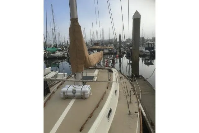 Slide: The Image of 1980 CAL 39 sailboat docked in a marina, featuring a covered mast and calm waters. - 13