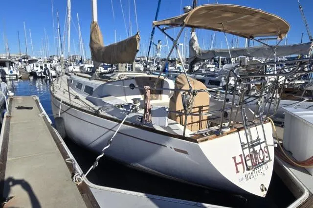Slide: The Image of 1980 CAL 39 sailboat docked in marina, featuring white hull and tan sail cover. - 22
