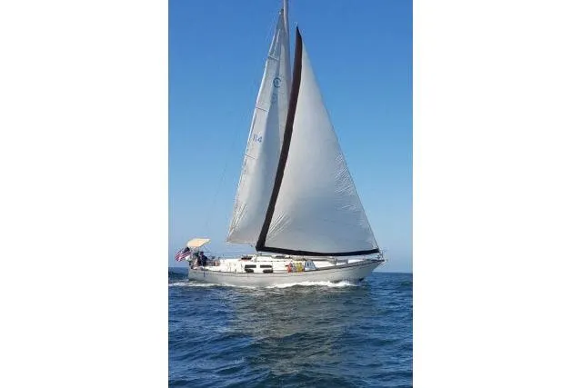 Slide: The Image of 1980 CAL 39 sailboat navigating on open water under clear blue skies. - 23