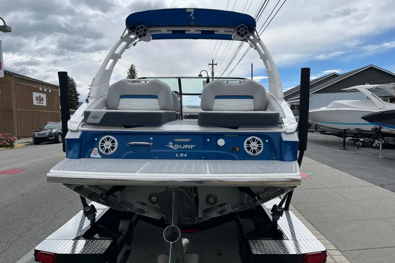 Slide: The Image of 2024 Regal LS4 Surf boat, rear view, parked on trailer, showcasing sleek design and features. - 3