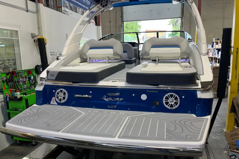 Slide: The Image of 2024 Regal LS4 Surf boat in a workshop, showcasing rear seating and audio system. - 5