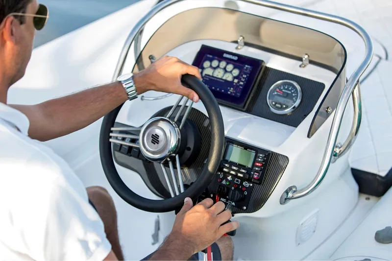 Slide: The Image of Manufacturer Provided Image: Person steering 2025 Walker Bay Generation 450 DLX boat, focusing on dashboard controls. - 5