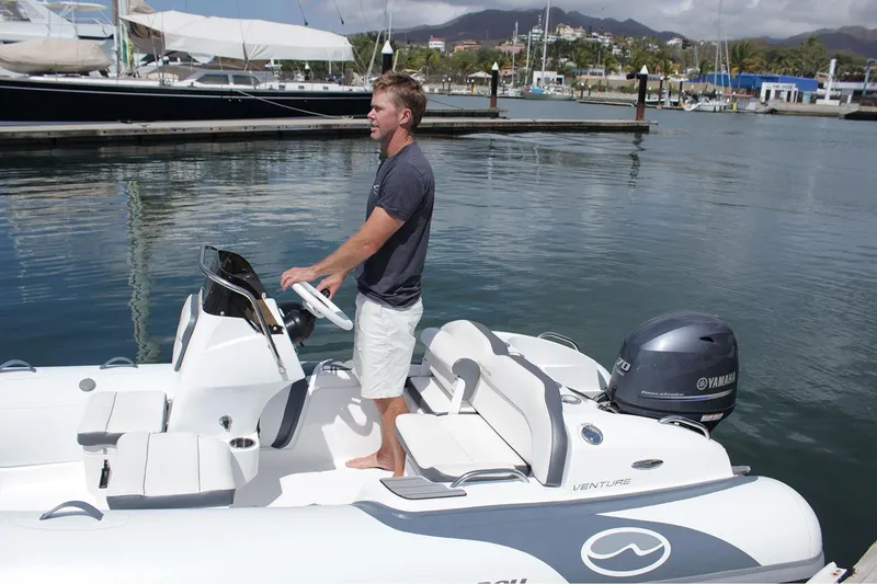 Slide: The Image of Manufacturer Provided Image: Man steering 2025 Walker Bay Venture 14 boat in marina. - 6