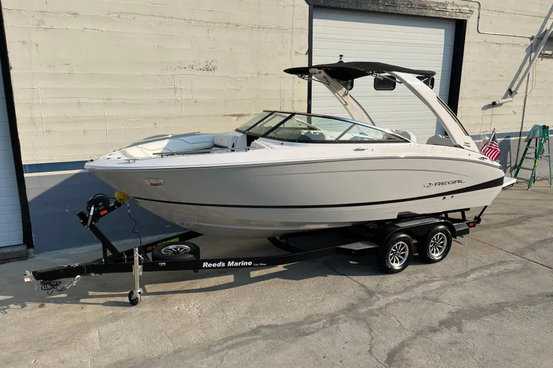The Image of 2025 Regal LS4 boat on trailer, parked outside a garage. - 0