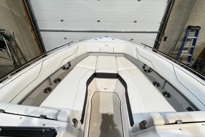 Slide: The Image of 2025 Regal LS4 boat interior with white seating and cup holders in a garage setting. - 8