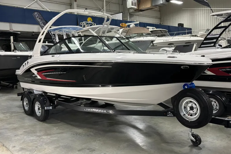 The Image of 2026 Chaparral 21 SSi OB boat on trailer in showroom, sleek black and white design. - 0