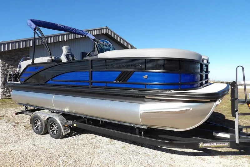 The Image of 2026 Bennington M Quad Bench 22 MFB pontoon boat on trailer, blue and black design. - 1