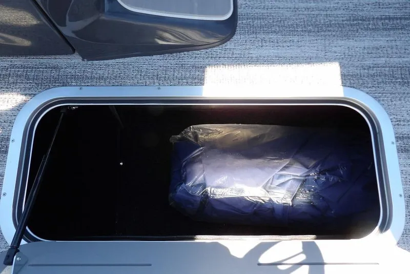 Slide: The Image of Storage compartment of 2026 Bennington M Quad Bench 22 MFB boat, open with contents inside. - 22