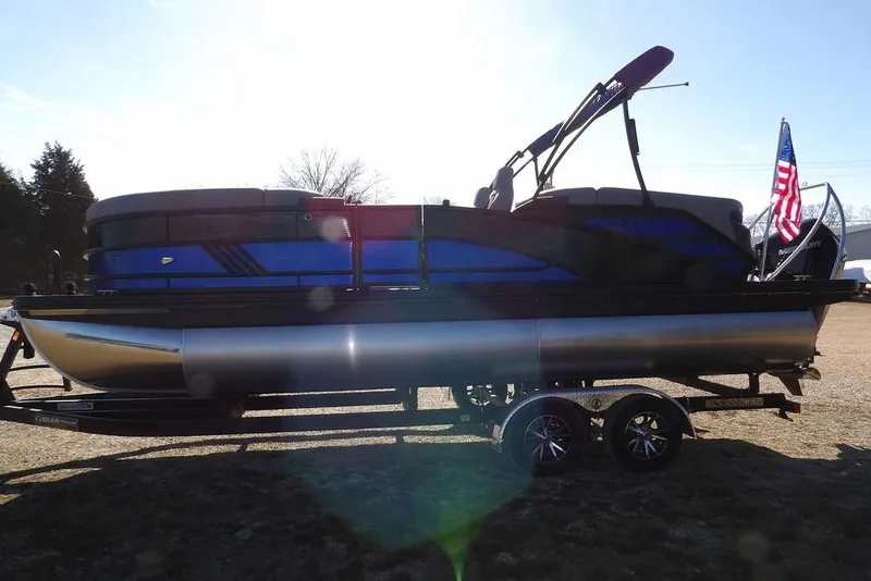 Slide: The Image of 2026 Bennington M Quad Bench 22 MFB pontoon boat with American flag, parked on trailer. - 8