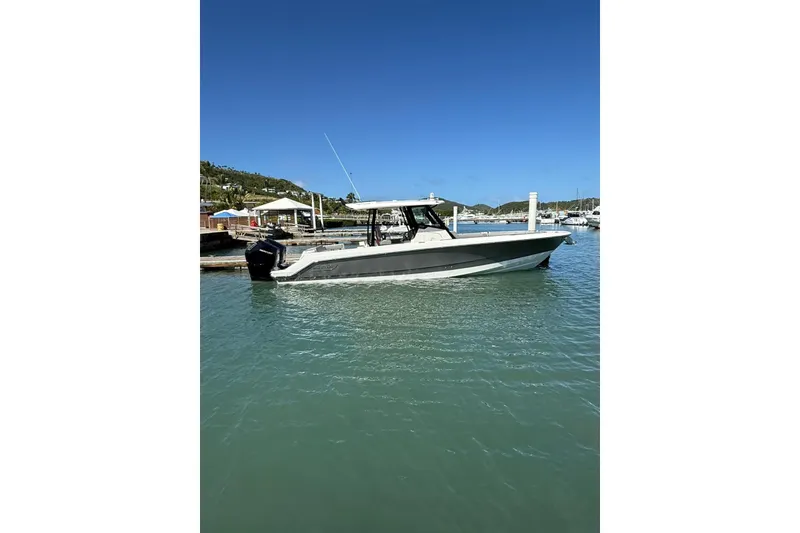 The Image of 2023 Boston Whaler 360 Outrage boat docked in a sunny marina. - 1