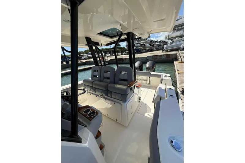 Slide: The Image of 2023 Boston Whaler 360 Outrage boat interior with seating and console, docked at marina. - 4