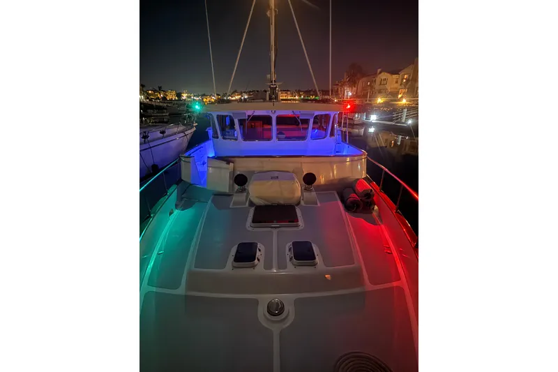 Slide: The Image of 1989 Nordhavn 46 yacht illuminated at night with colorful deck lights. - 10