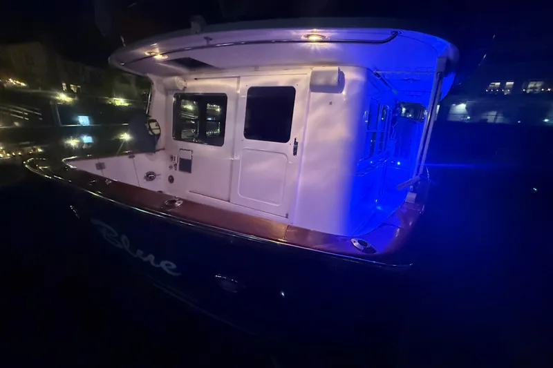 Slide: The Image of 1989 Nordhavn 46 yacht illuminated at night with blue lights in a marina. - 11