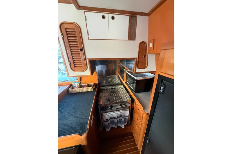 Slide: The Image of Cozy kitchen area in a 1989 Nordhavn 46 yacht, featuring a stove and storage. - 21