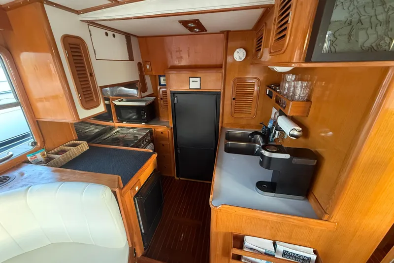 Slide: The Image of 1989 Nordhavn 46 yacht kitchen with wooden cabinetry, appliances, and seating area. - 22