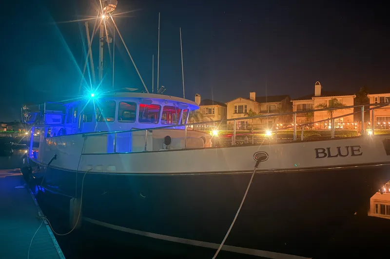 Slide: The Image of 1989 Nordhavn 46 yacht docked at night, illuminated by colorful lights. - 27