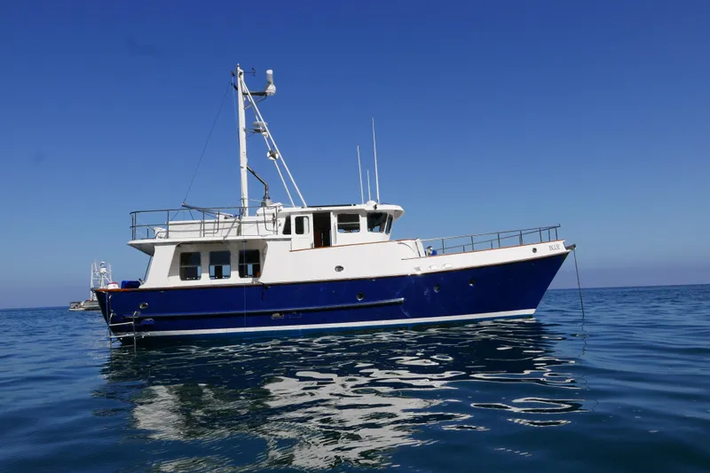 Slide: The Image of 1989 Nordhavn 46 yacht anchored on calm blue sea under clear sky. - 3