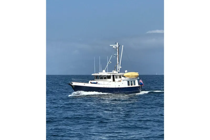 Slide: The Image of 1989 Nordhavn 46 yacht cruising on open sea under clear blue sky. - 30