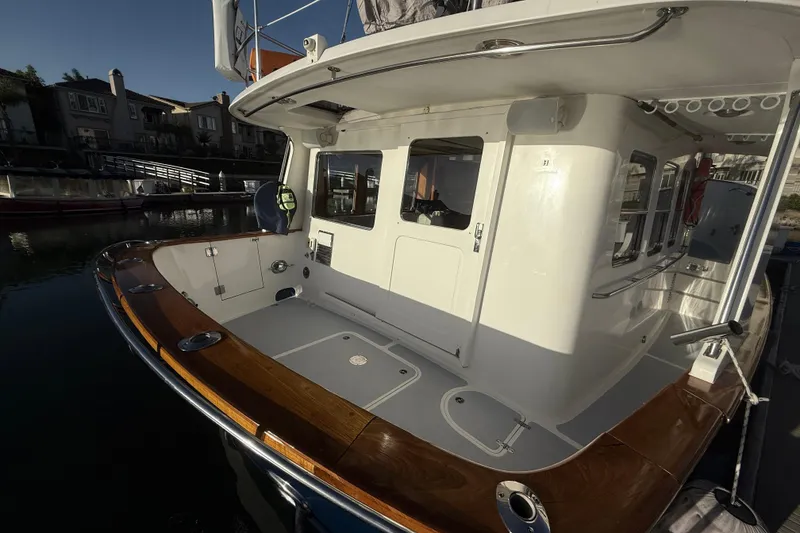 Slide: The Image of 1989 Nordhavn 46 yacht with wooden deck, docked in a serene marina setting. - 7
