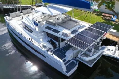 Slide: The Image of 2021 Bali 5.4 catamaran with solar panels docked by lush greenery. - 29