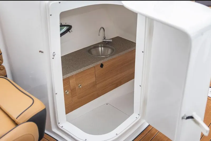 Slide: The Image of Manufacturer Provided Image: Interior of 2026 Hurricane SunDeck 2690 OB boat featuring a compact sink and wooden cabinetry. - 8