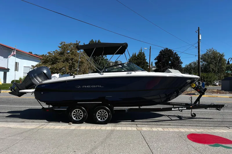 The Image of 2026 Regal LX2 boat on trailer, covered, parked on street. - 0