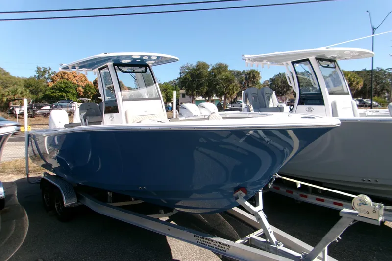 The Image of 2025 Sportsman Open 252 Center Console boat on trailer, blue hull, outdoor display. - 0