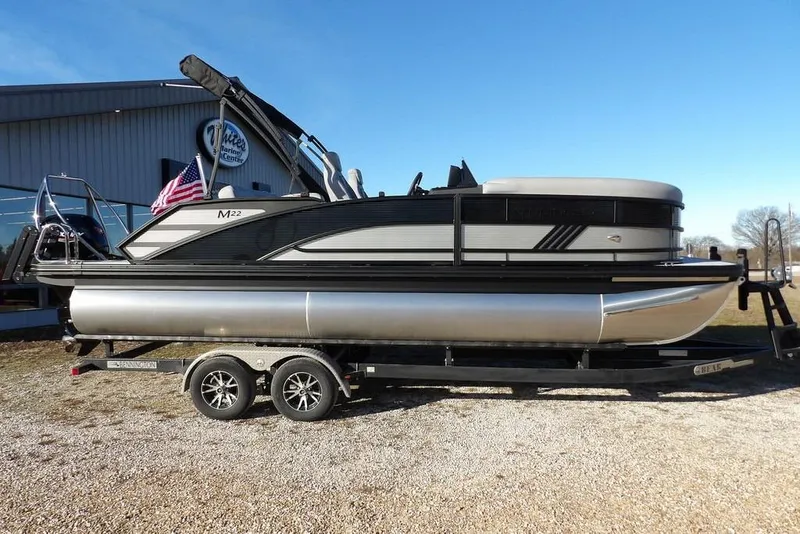 Slide: The Image of 2026 Bennington M Swingback 22 MSB pontoon boat on trailer, parked outdoors. - 3