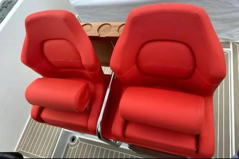 Slide: The Image of Red cushioned seat on 2021 Nimbus T8 boat, with Mercury engine in background. - 10
