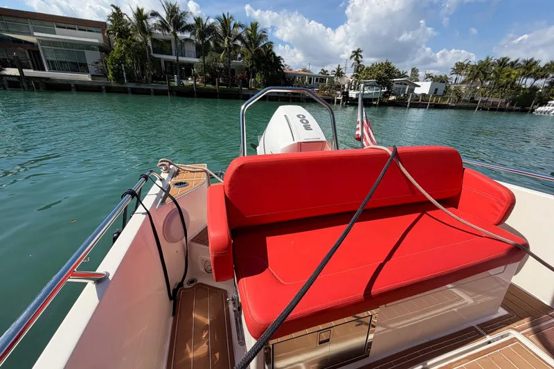 Slide: The Image of 2021 Nimbus T8 boat with red seating, docked by waterfront homes. - 56