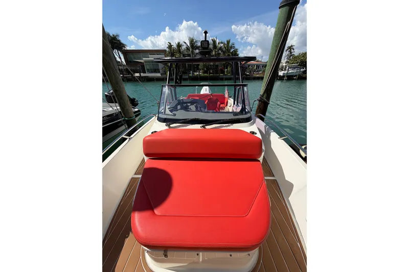 Slide: The Image of 2021 Nimbus T8 boat with red seating, docked by a waterfront under a clear sky. - 59