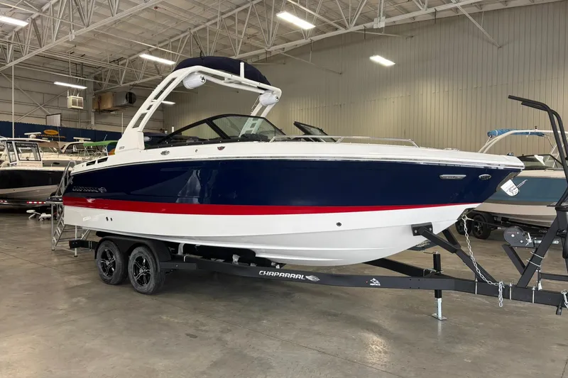 The Image of 2026 Chaparral SSX 6 boat in showroom, blue and white with red stripe, on trailer. - 0