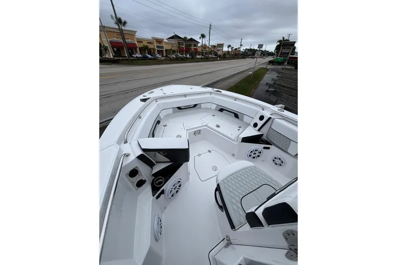 Slide: The Image of 2025 Blackfin 252 CC boat interior with seating and speakers, parked near a road. - 3
