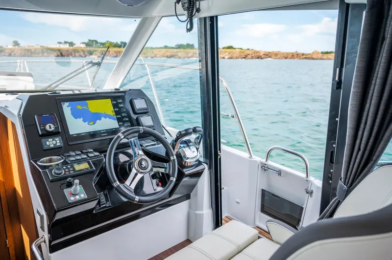 Slide: The Image of 2026 Beneteau Antares 11 cockpit with navigation system, steering wheel, and ocean view. - 9