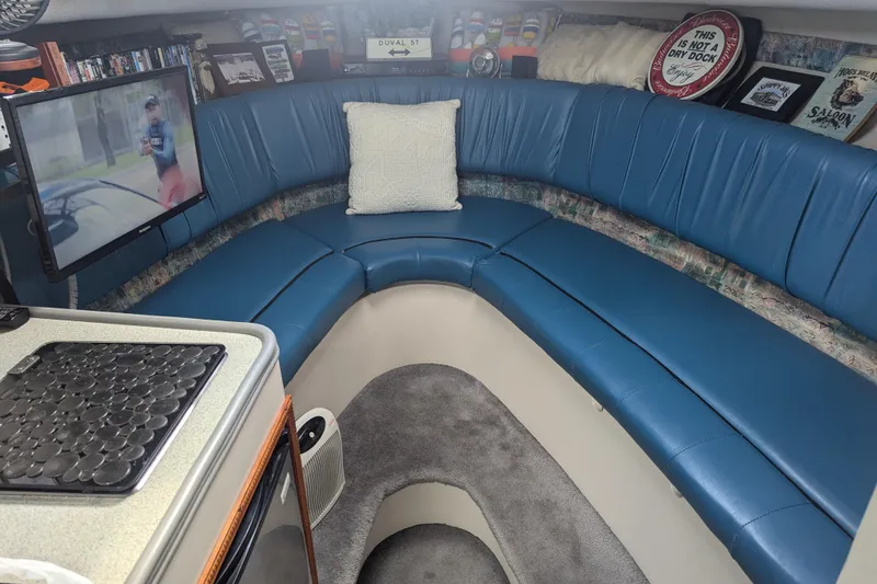 Slide: The Image of 1995 Carver 250 Express cabin with blue seating, TV, and decor. - 7