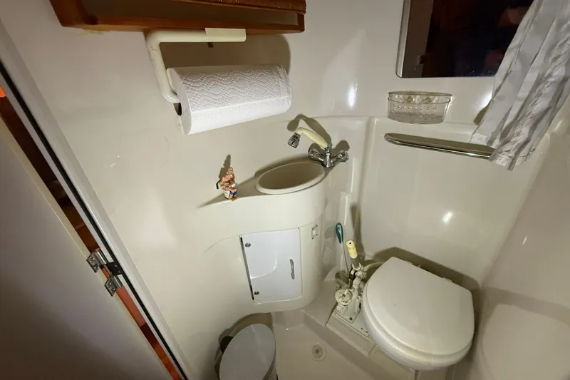 Slide: The Image of Compact bathroom in a 1995 Carver 250 Express boat, featuring a toilet and sink. - 12