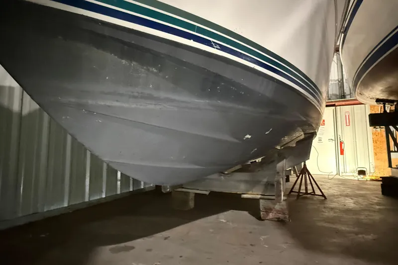 Slide: The Image of 1995 Carver 250 Express boat hull in storage, showing underside and support stands. - 25