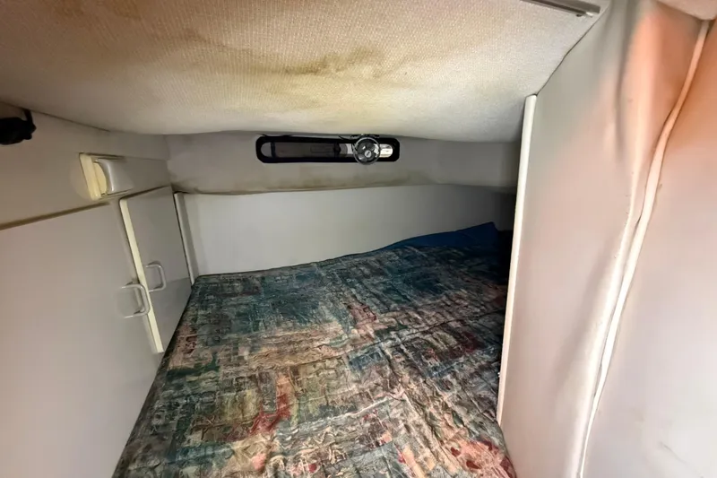 Slide: The Image of Interior cabin of a 1995 Carver 250 Express boat with a patterned bedspread. - 9