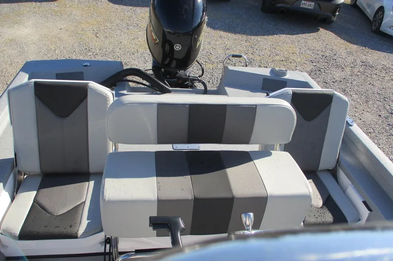 Slide: The Image of 2026 Vexus Defender 201 boat interior with seating and motor, parked on gravel. - 12