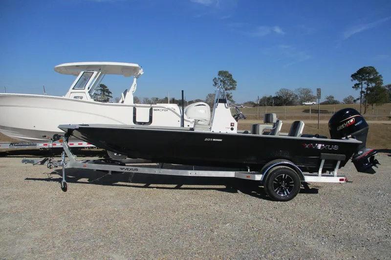 Slide: The Image of 2026 Vexus Defender 201 boat on trailer, parked outdoors under clear blue sky. - 5