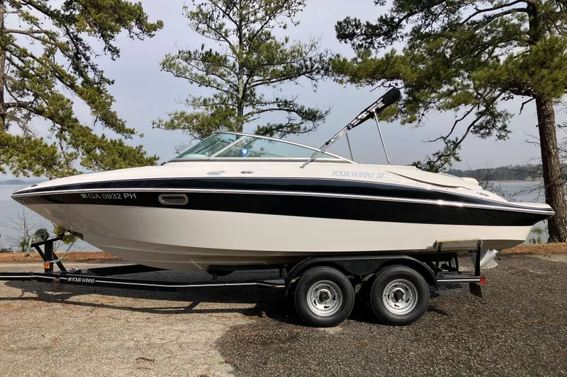 The Image of 2006 Four Winns 240 Horizon boat on trailer, parked near a lake with trees. - 0